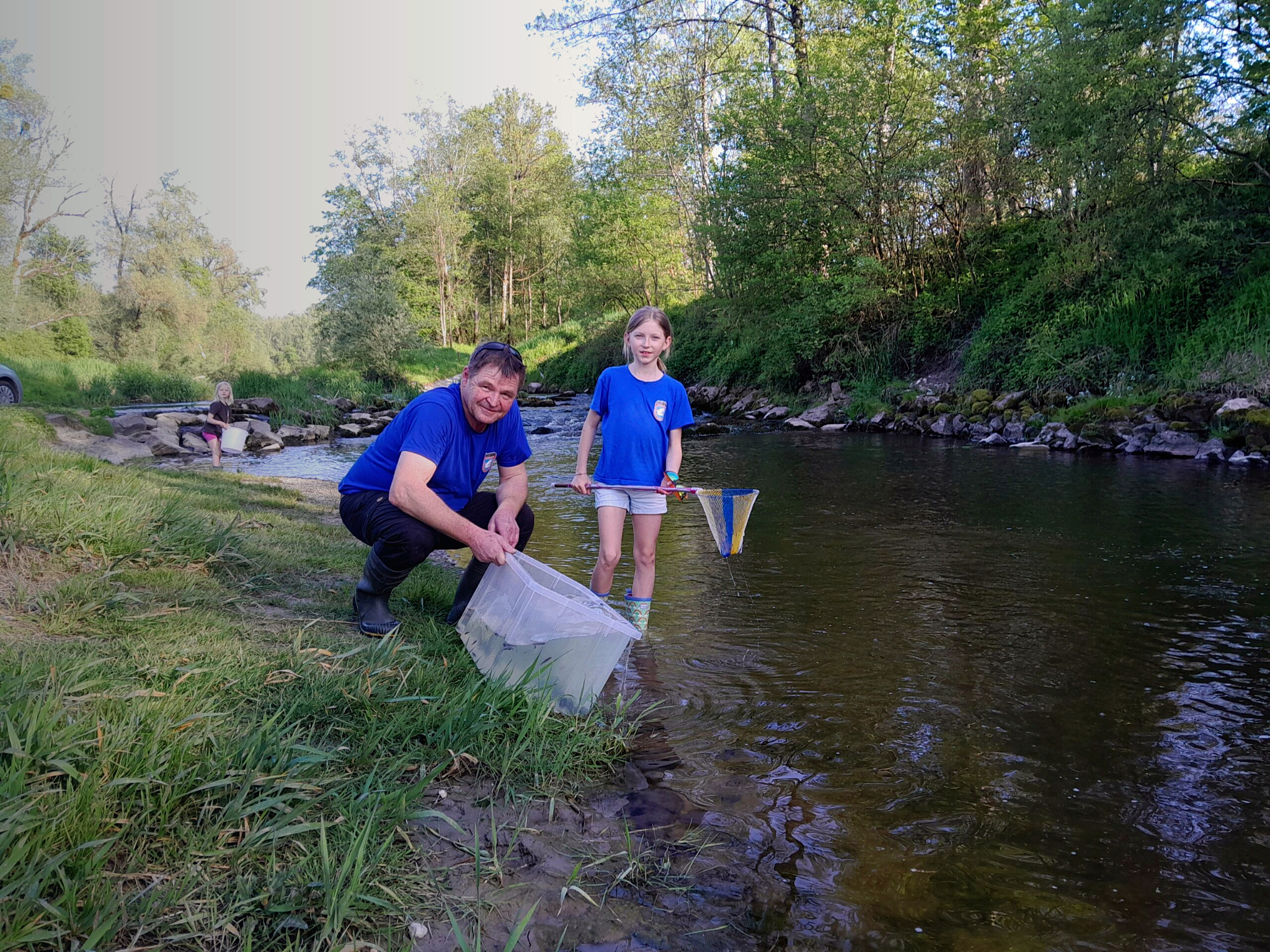 Vereinsmitglieder beim Fischbesatz an einem Bach