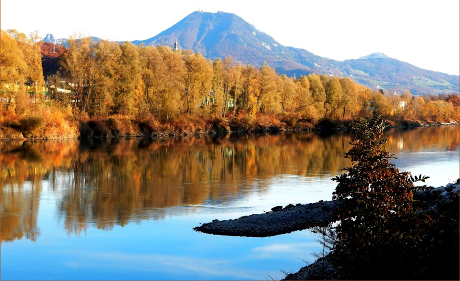 Die Salzach im Herbst mit Berg im Hintergrund und Spiegelungen im Wasser